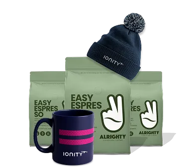 Set of three green coffee bags labeled 'Easy Espresso' with a navy blue Ionity mug and a navy blue knit beanie with pom-pom, both branded Ionity.
