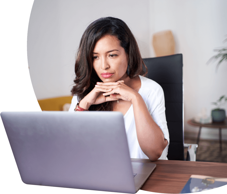 Mujer concentrada mirando la pantalla de una laptop en un escritorio en una oficina.