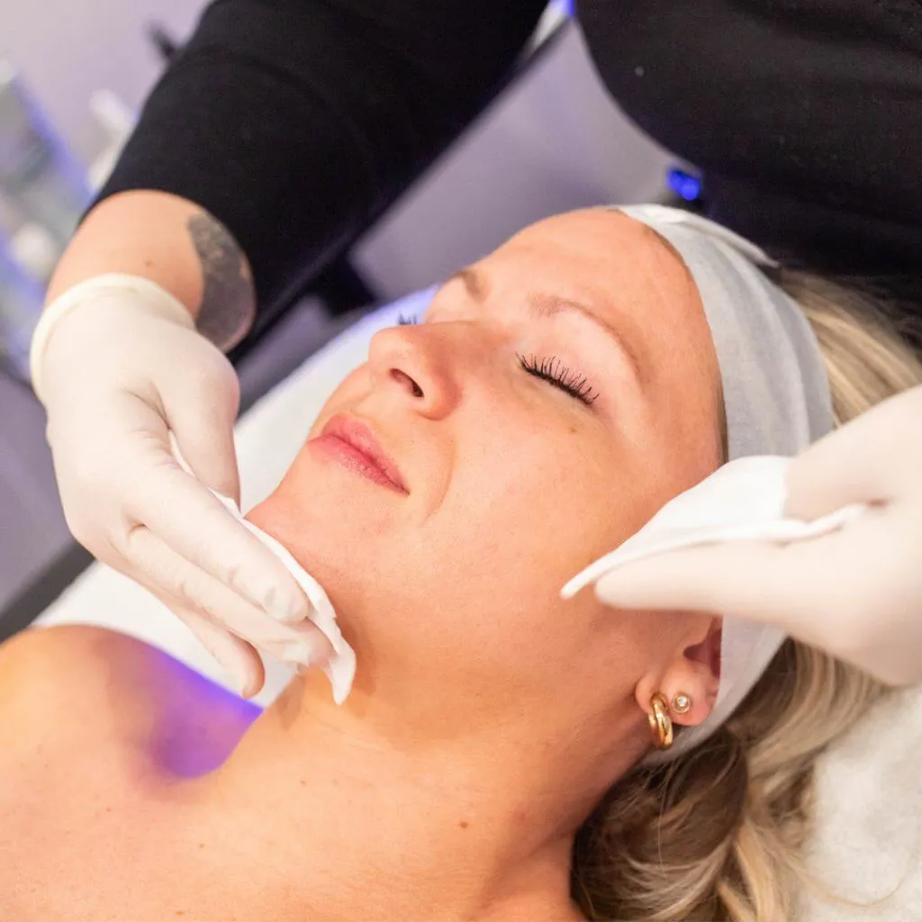 Application of facial products with cotton pads to a woman's face