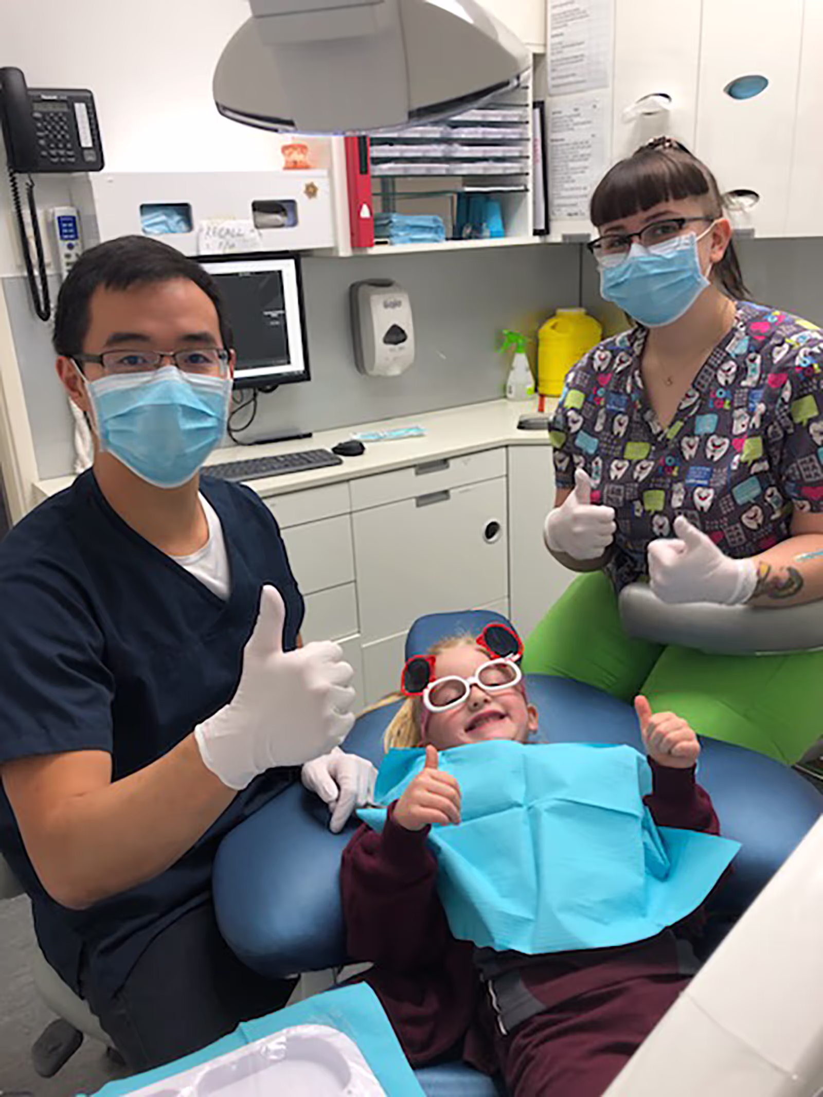 Two dentists working on a child getting dental treatment