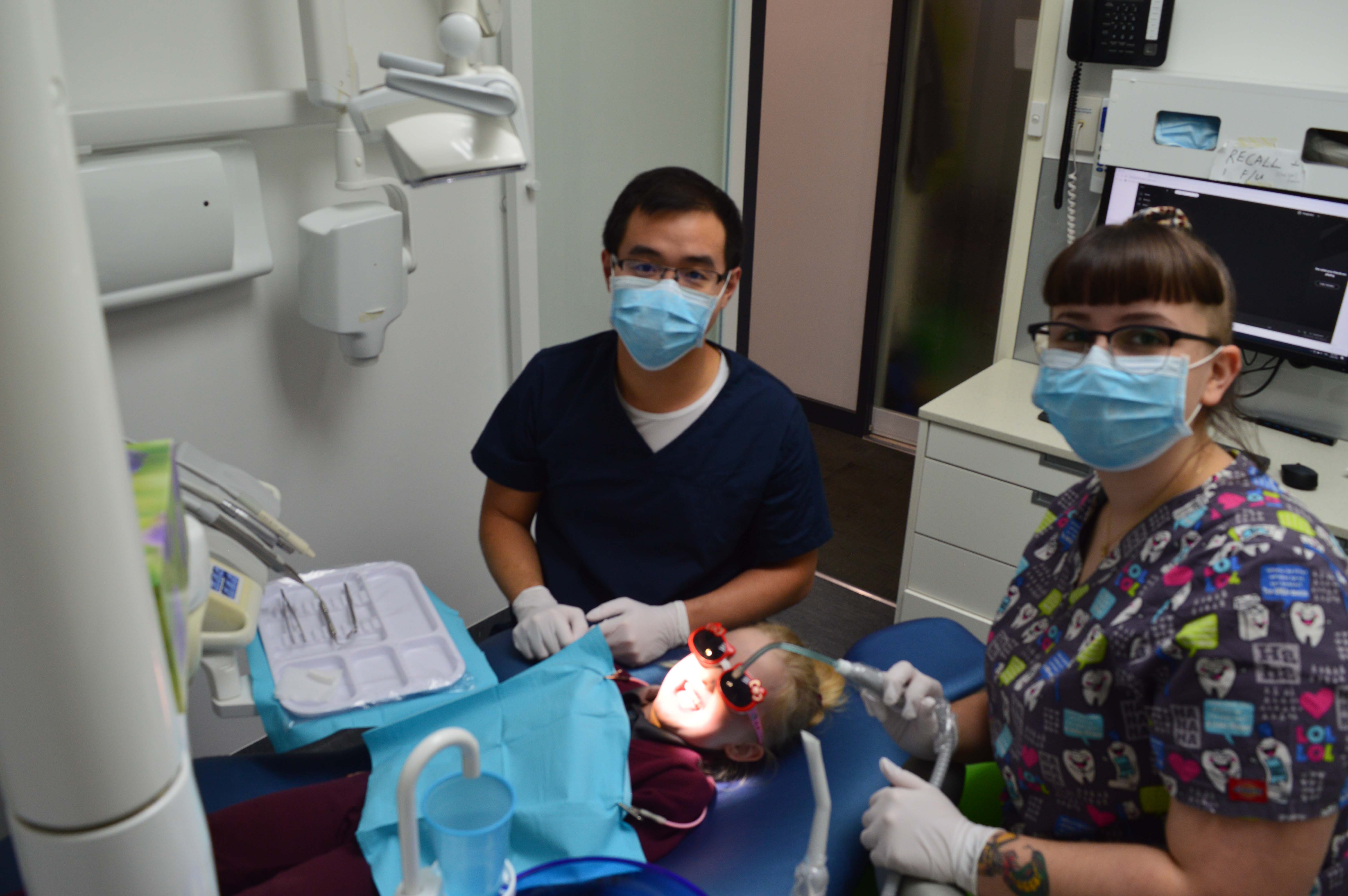 Two dentists standing over a child patient