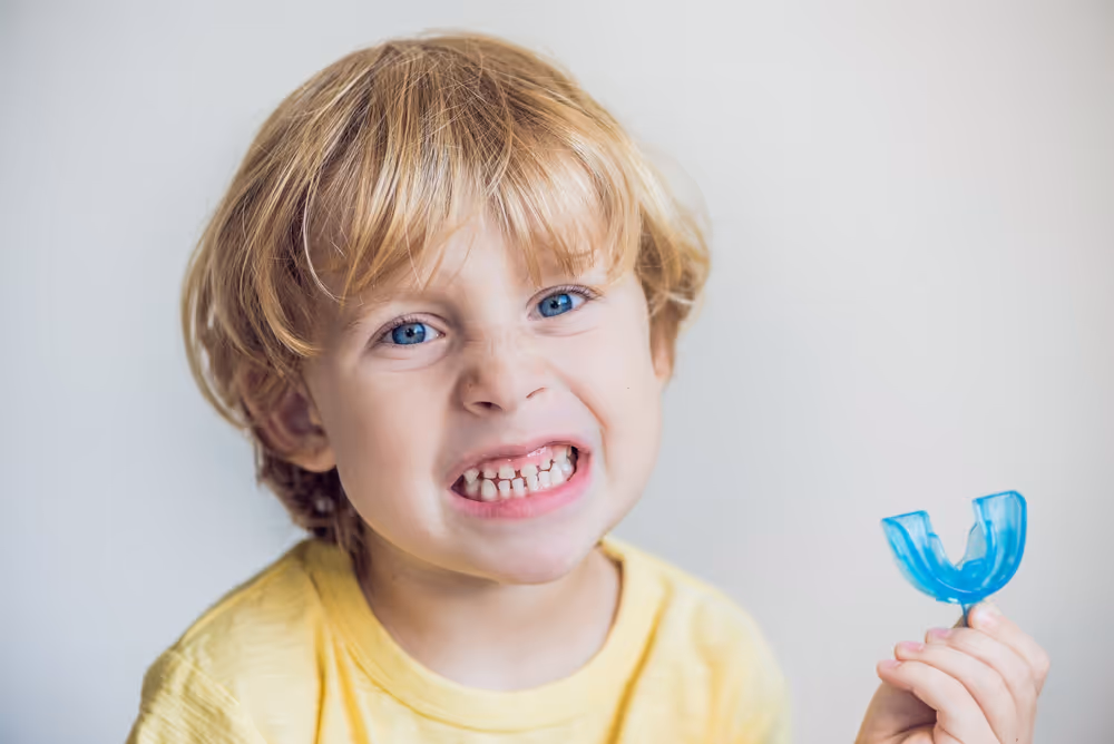 A small child holding a dental retainer