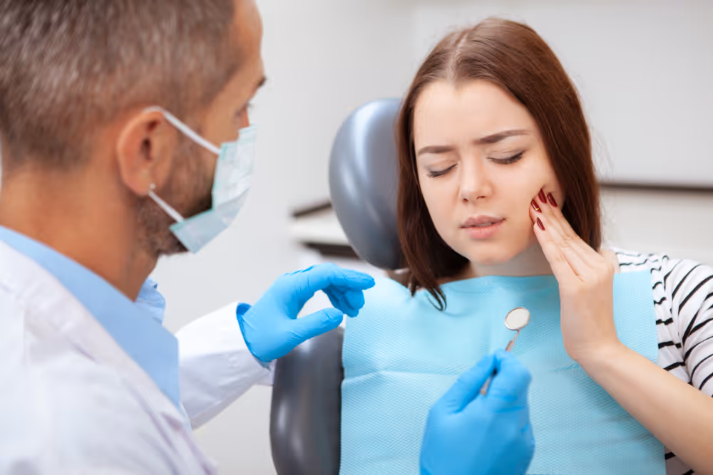Woman touching cheek displaying dental pain to dentist
