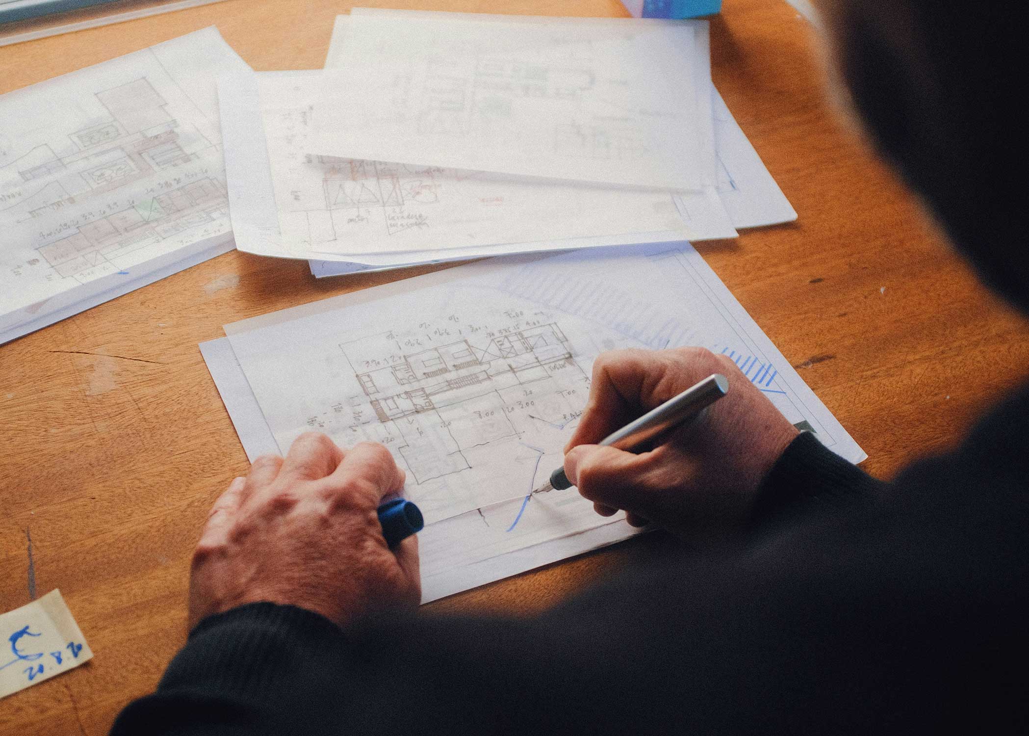 Man writing on house plans.