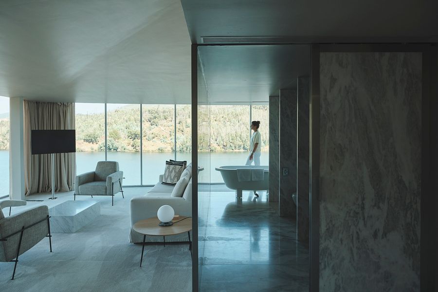 Marble-clad hotel suite with river-view seating area and freestanding bathtub, Douro Valley, Portugal
