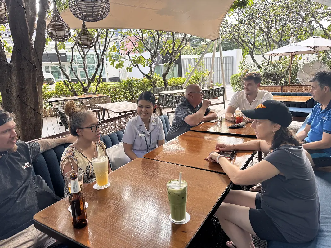 Christine enjoying a relaxed gathering with other patients and staff at the recovery hotel courtyard, sharing stories over drinks.