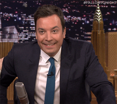 TV gif. Jimmy Fallon on The Tonight Show sits at his desk. He pumps his fist up and bites his lip in intense excitement. He yells, “Yes!” to pump up the audience.