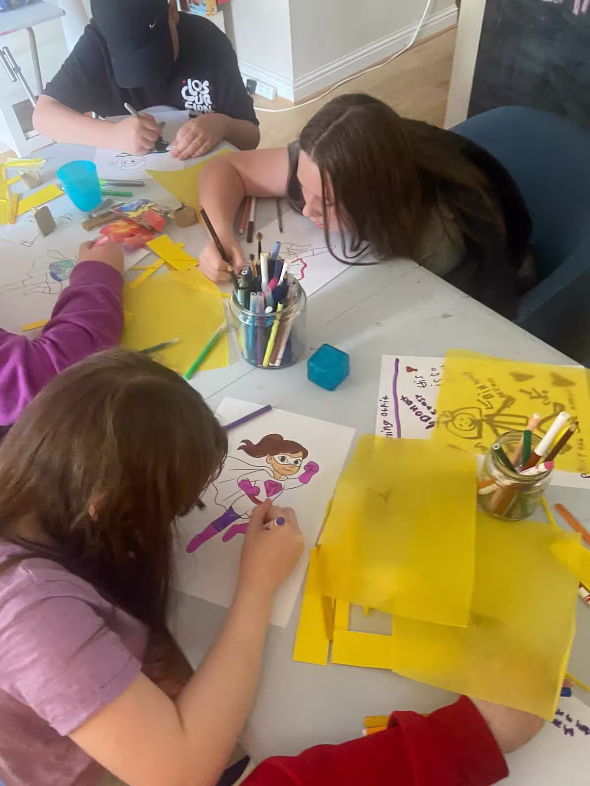 Group of young people at an arts and crafts table colouring in