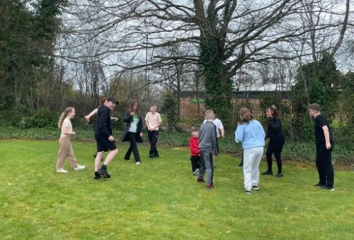 A group of young people playing an outdoor group game on grass