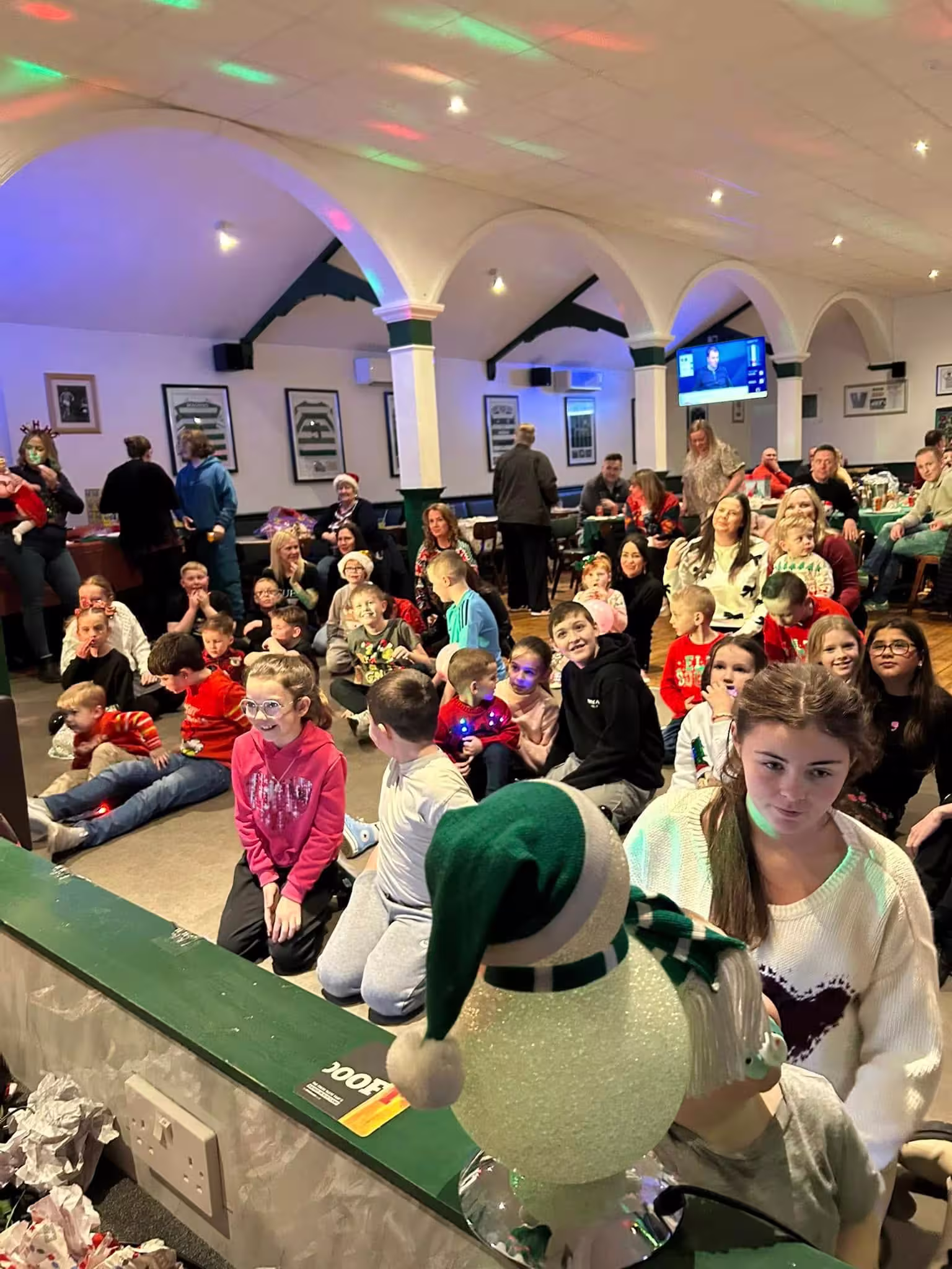 Families gathered at a Christmas event, seated whist watching a festive show.