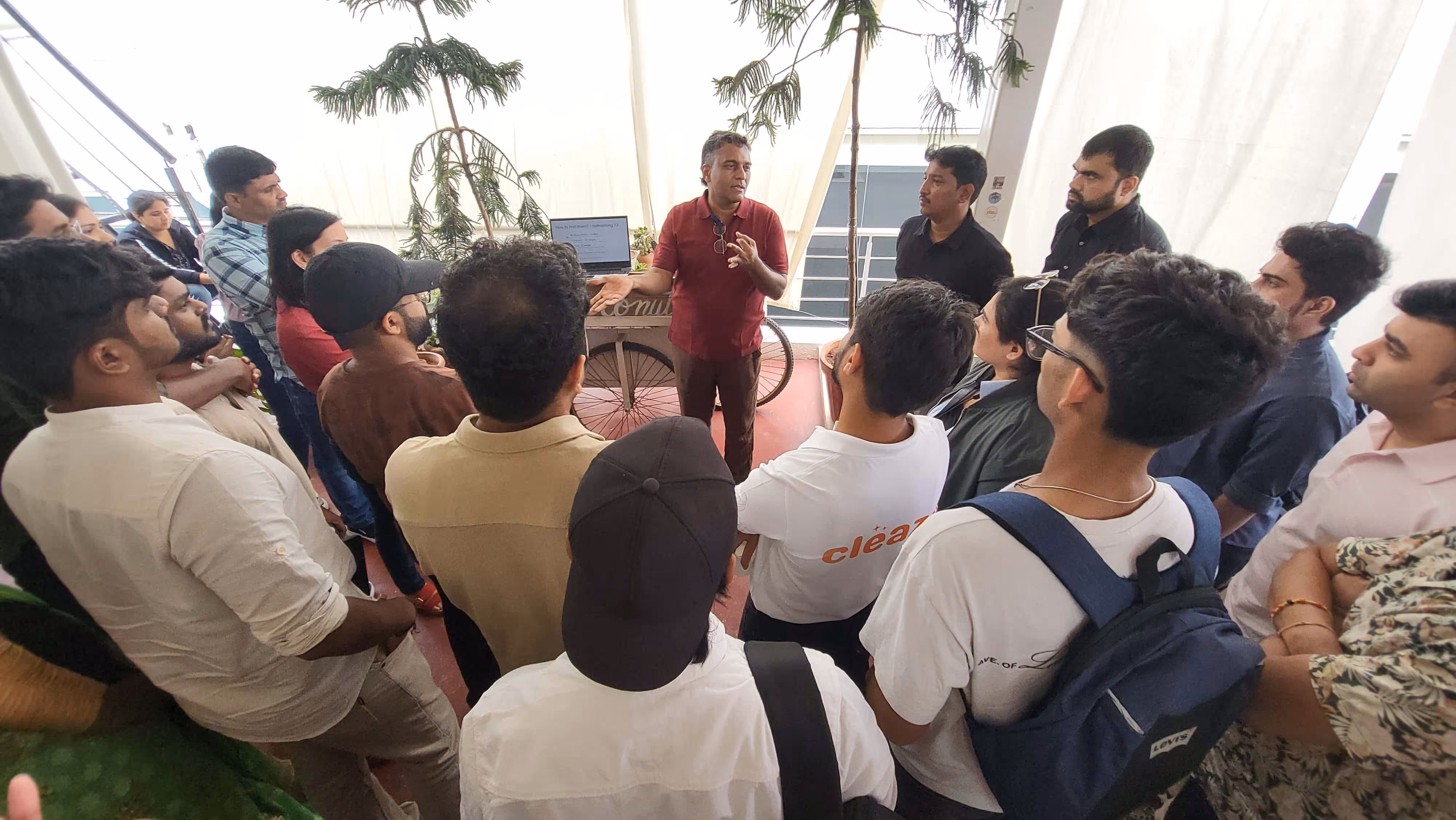 Three young adults gathered around a laptop, discussing and pointing at the screen in a well-lit room.