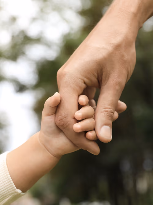 Ein Mann hält ein Kind an der Hand