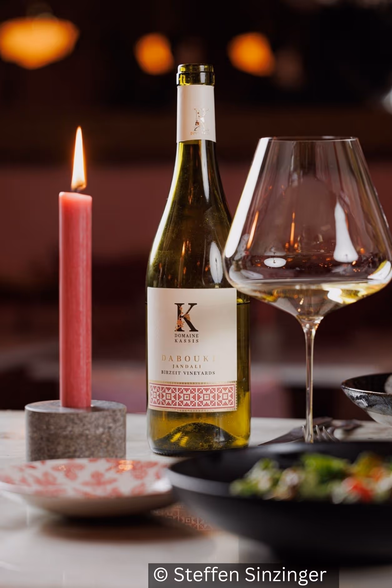 Wein, eine Kerze, und Speisen auf gedecktem Tisch