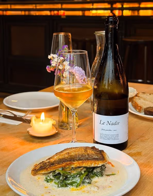 Fisch auf Teller mit Flasche und Glas Weiswein
