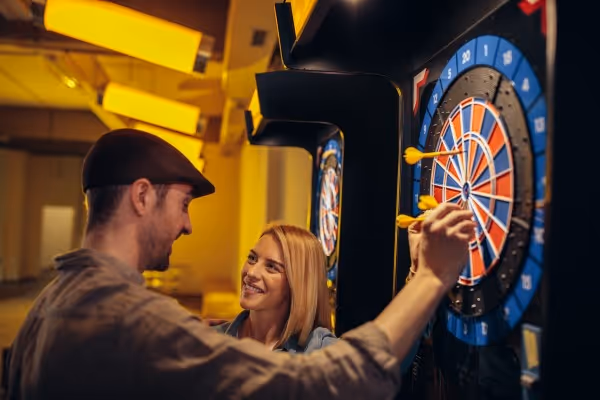 Mann zieht Dart aus Dartscheibe