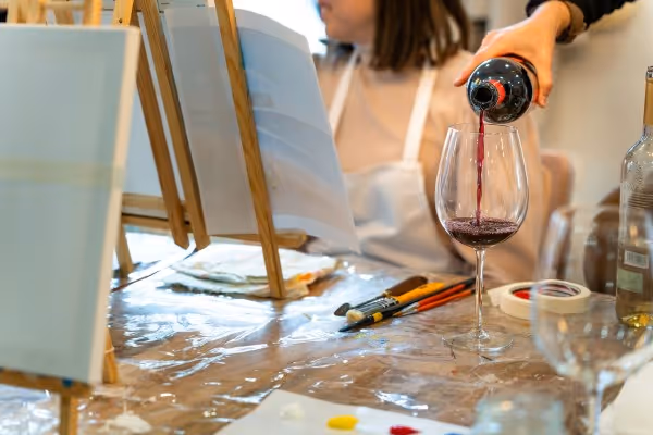 Frau gießt Glas Wein ein vor Mal-Leinwand