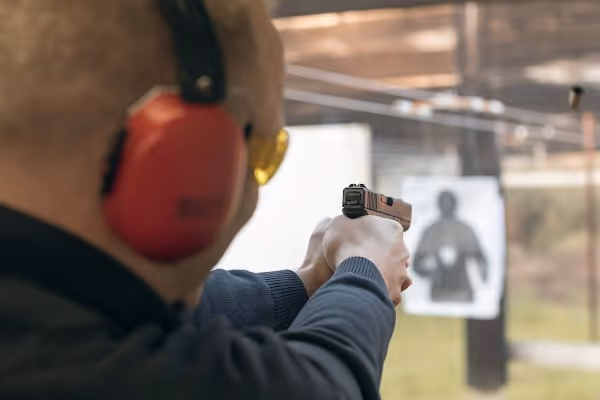 Mann schießt mit Pistole auf Zielscheibe