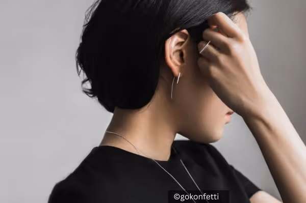 Frau zeigt ihren Ohrring am Ohr im Berliner Atelier