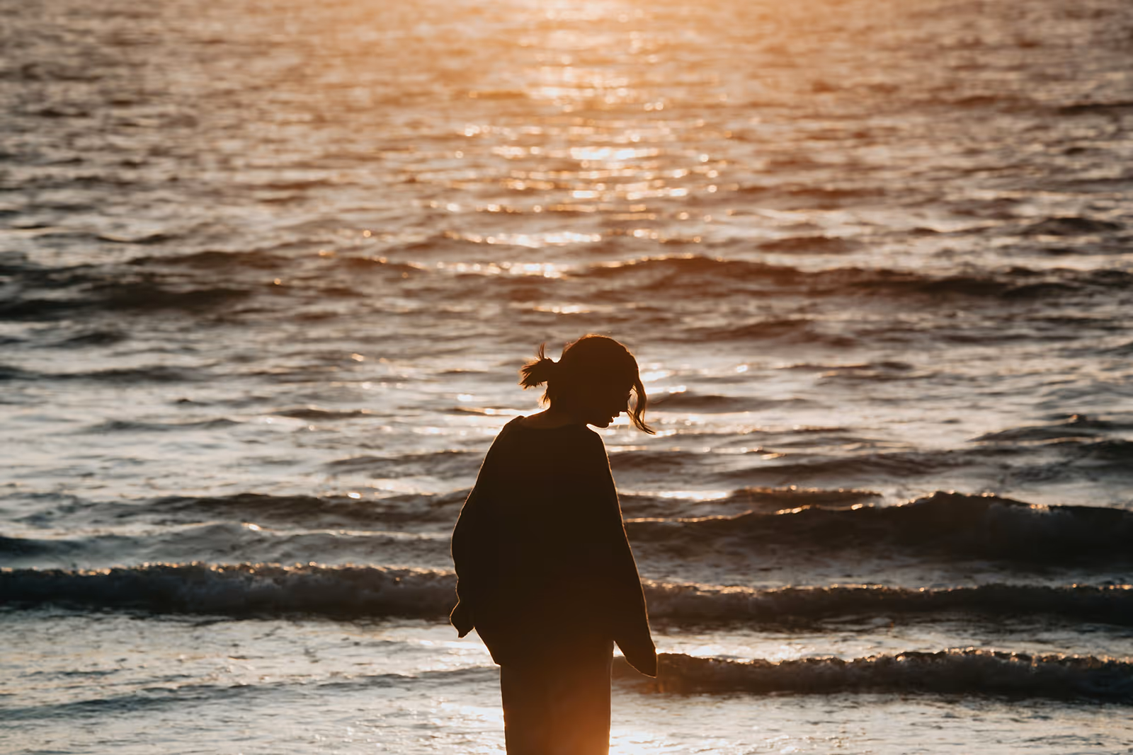 woman standing by the ocean alone
