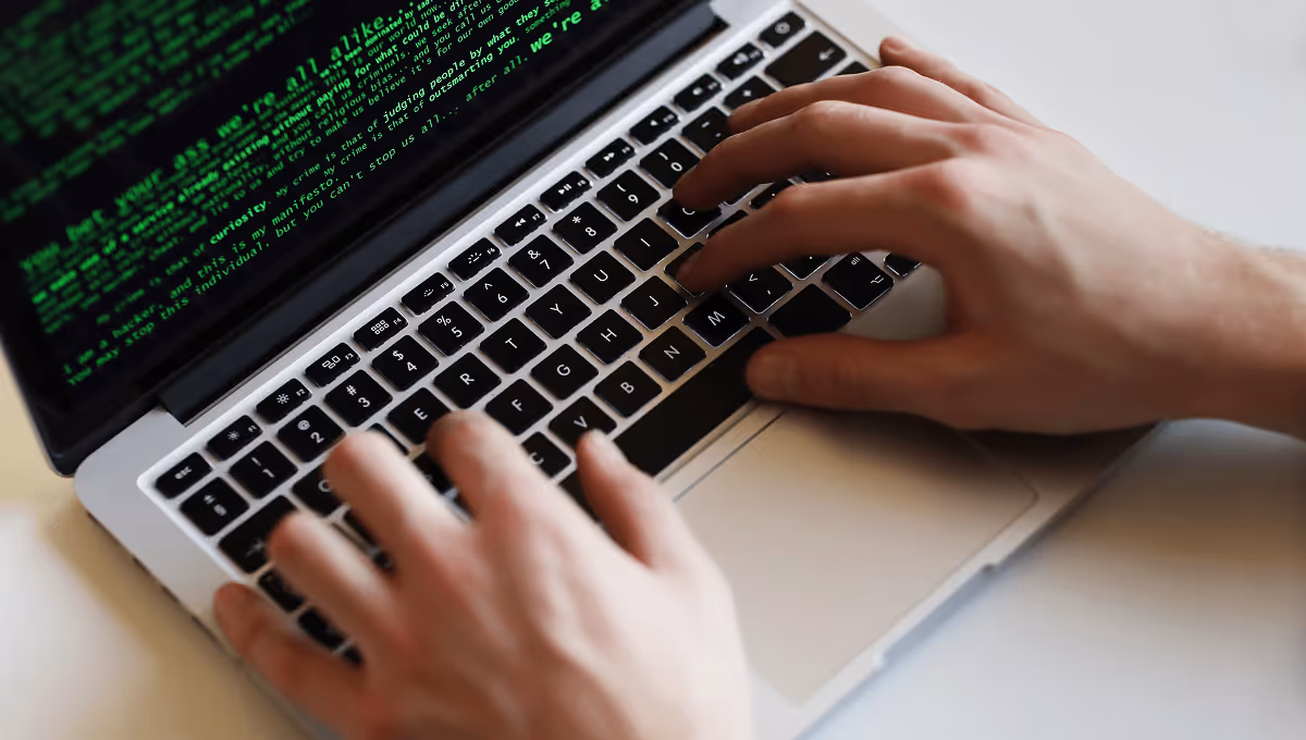 Hands typing code on laptop screen displaying hacker manifesto, expert cybersecurity and IT services in Luxembourg for robust digital defense.