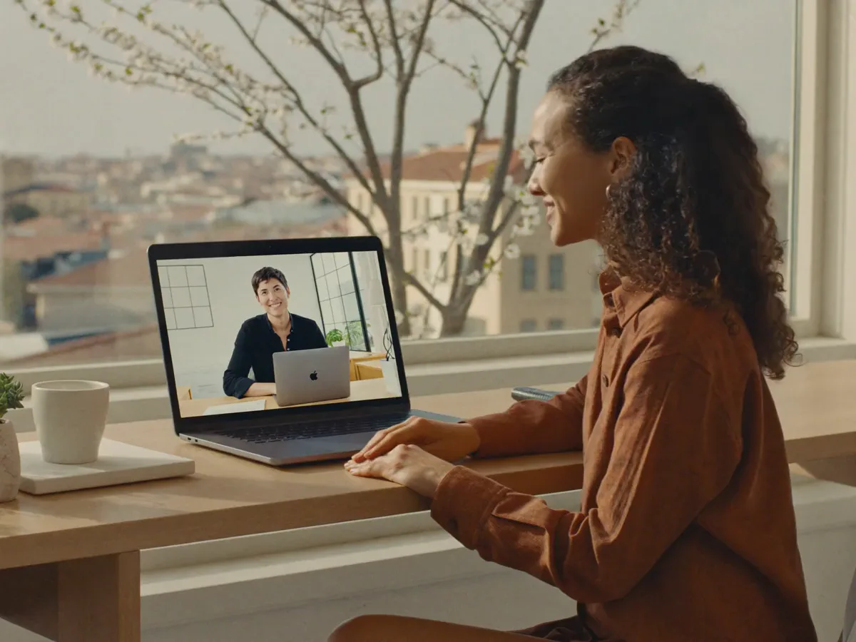 A remote professional in Buenos Aires smiles on a morning video call with her New York manager, both in daylight