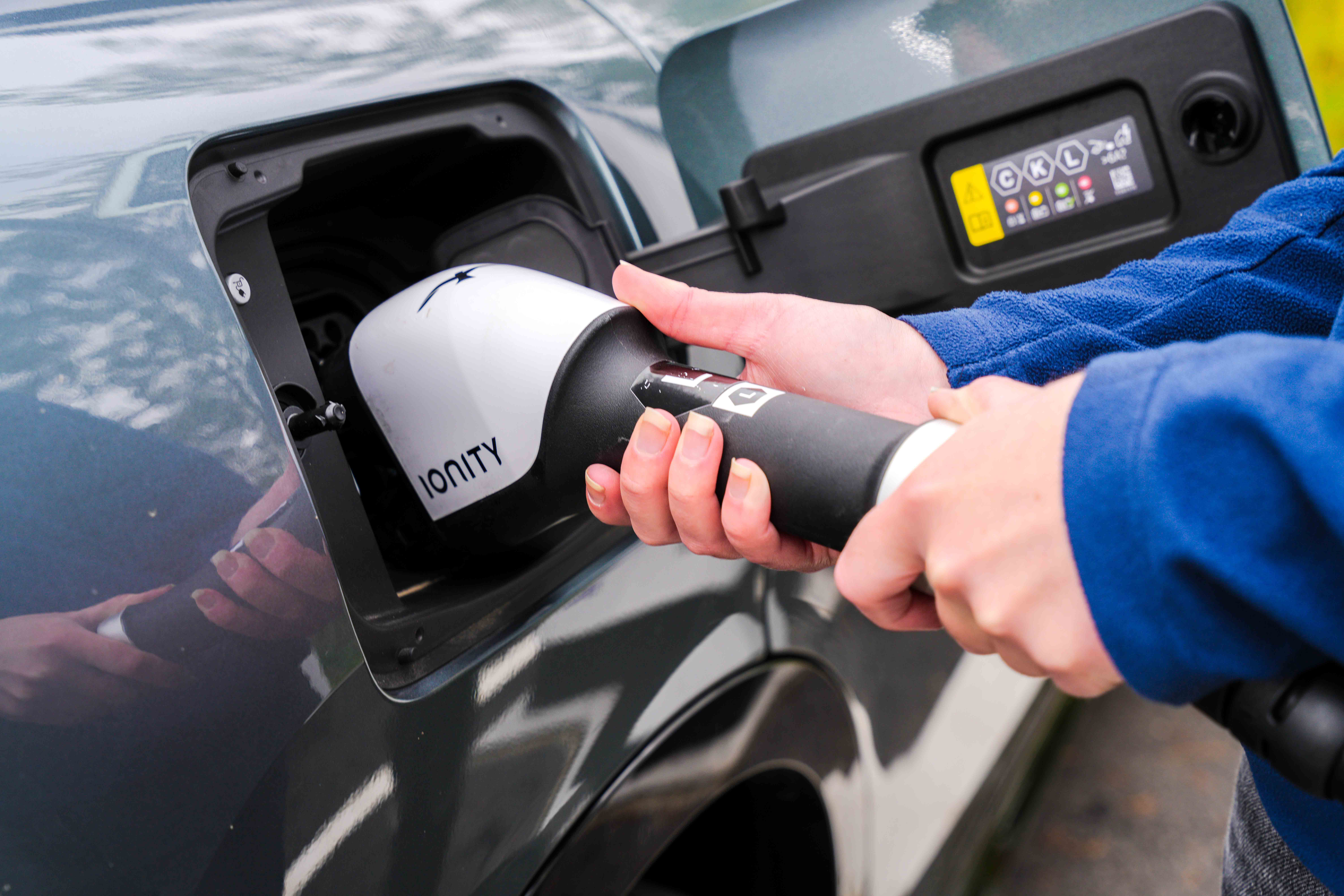 Close-up of a charging cable plugged into a dark grey electric car