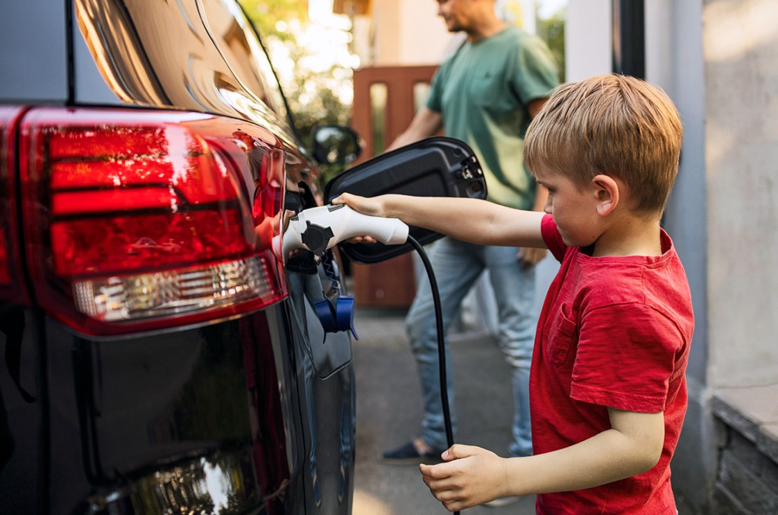 Kleiner Junge im roten T-Shirt lädt ein Elektroauto an einer IONITY-Ladestation