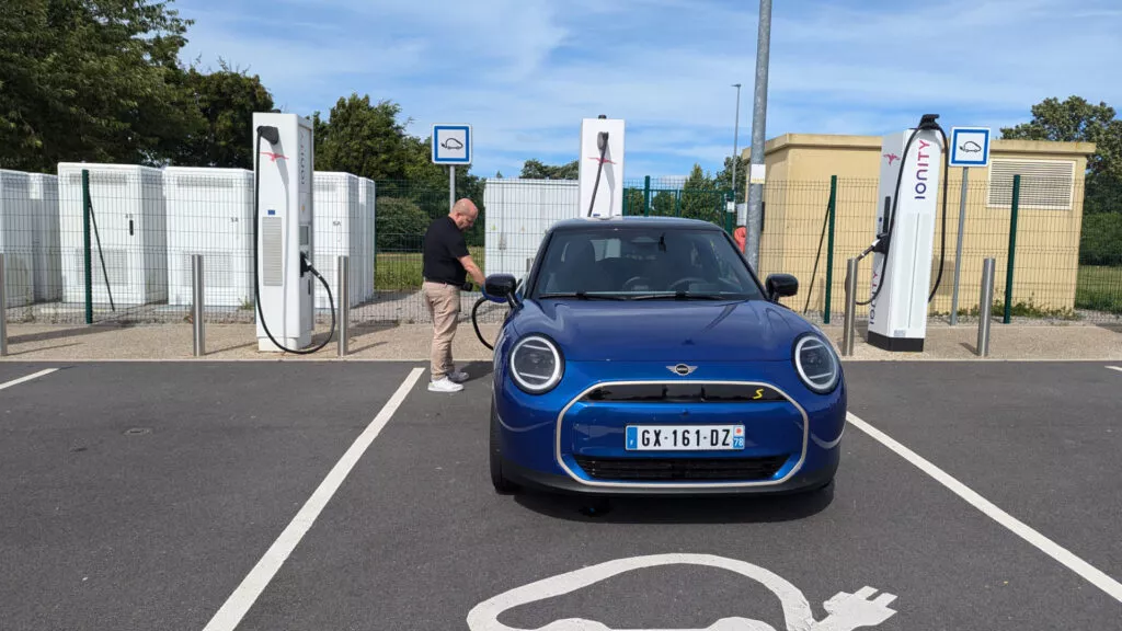 Homme recharge sa Mini Cooper bleue à une borne IONITY