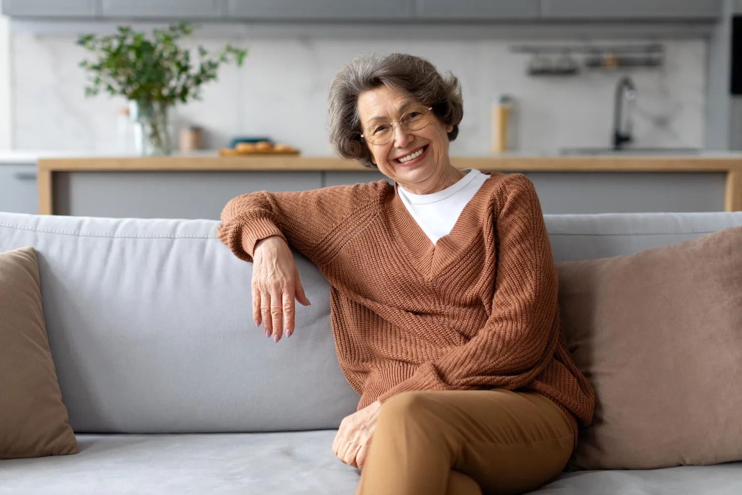 Happy senior lady resting on sofa and smiling to camera.