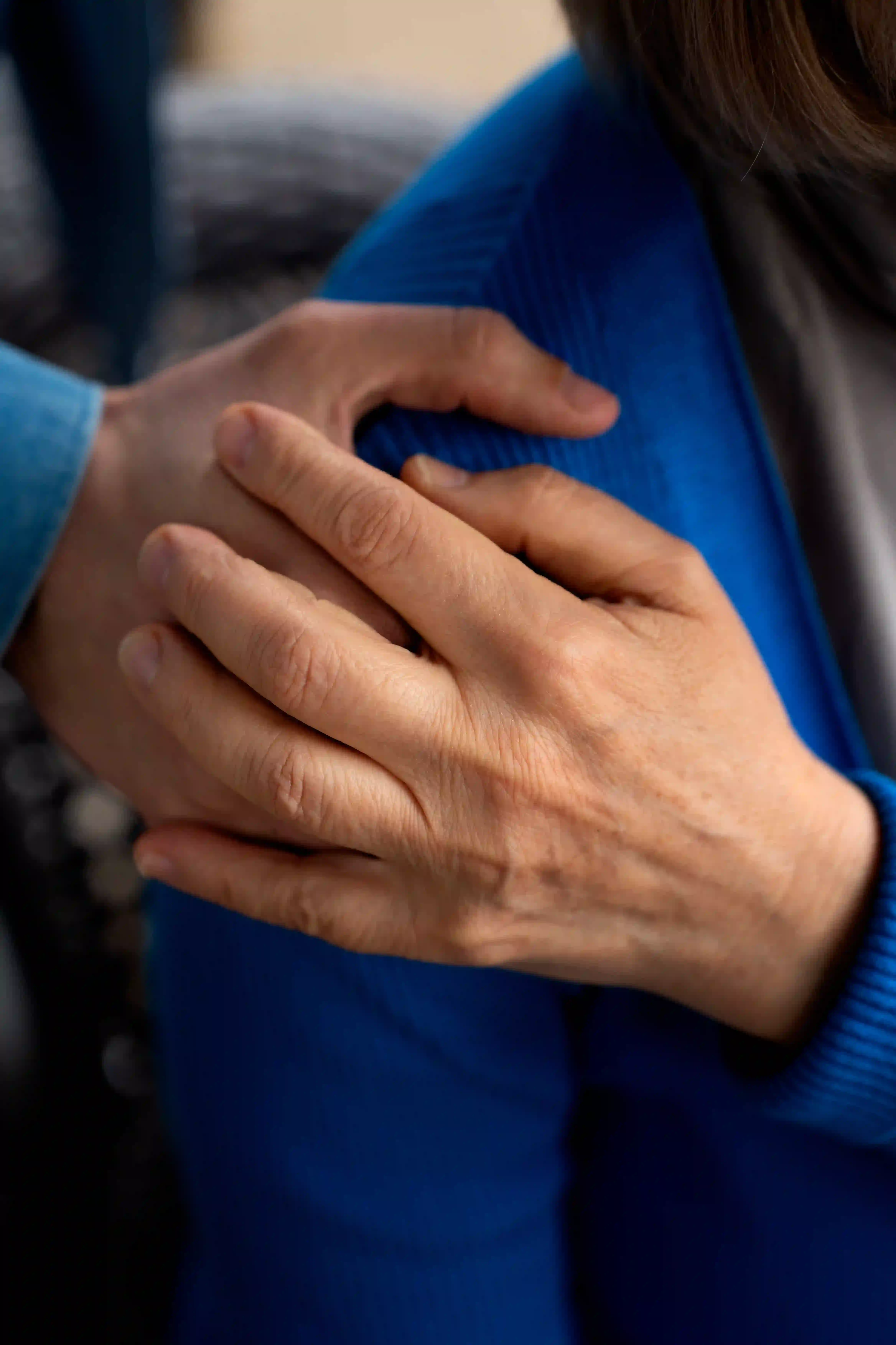 Close-up of a caregiver's hand gently supporting an elderly person's shoulder to provide comfort.