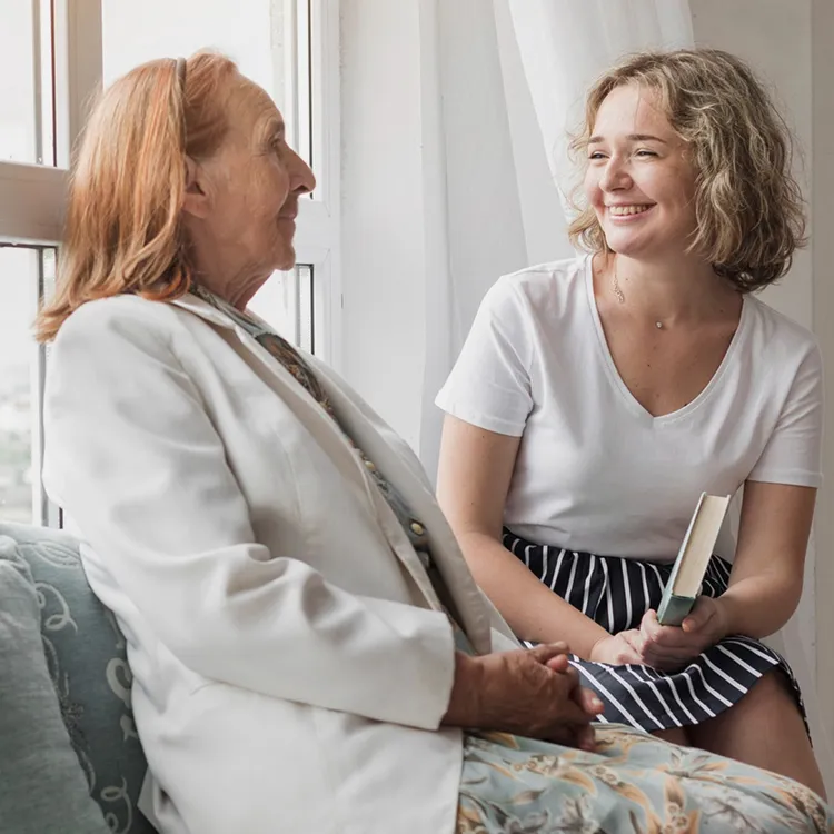 Smiling woman holding book sitting with her granny window sill