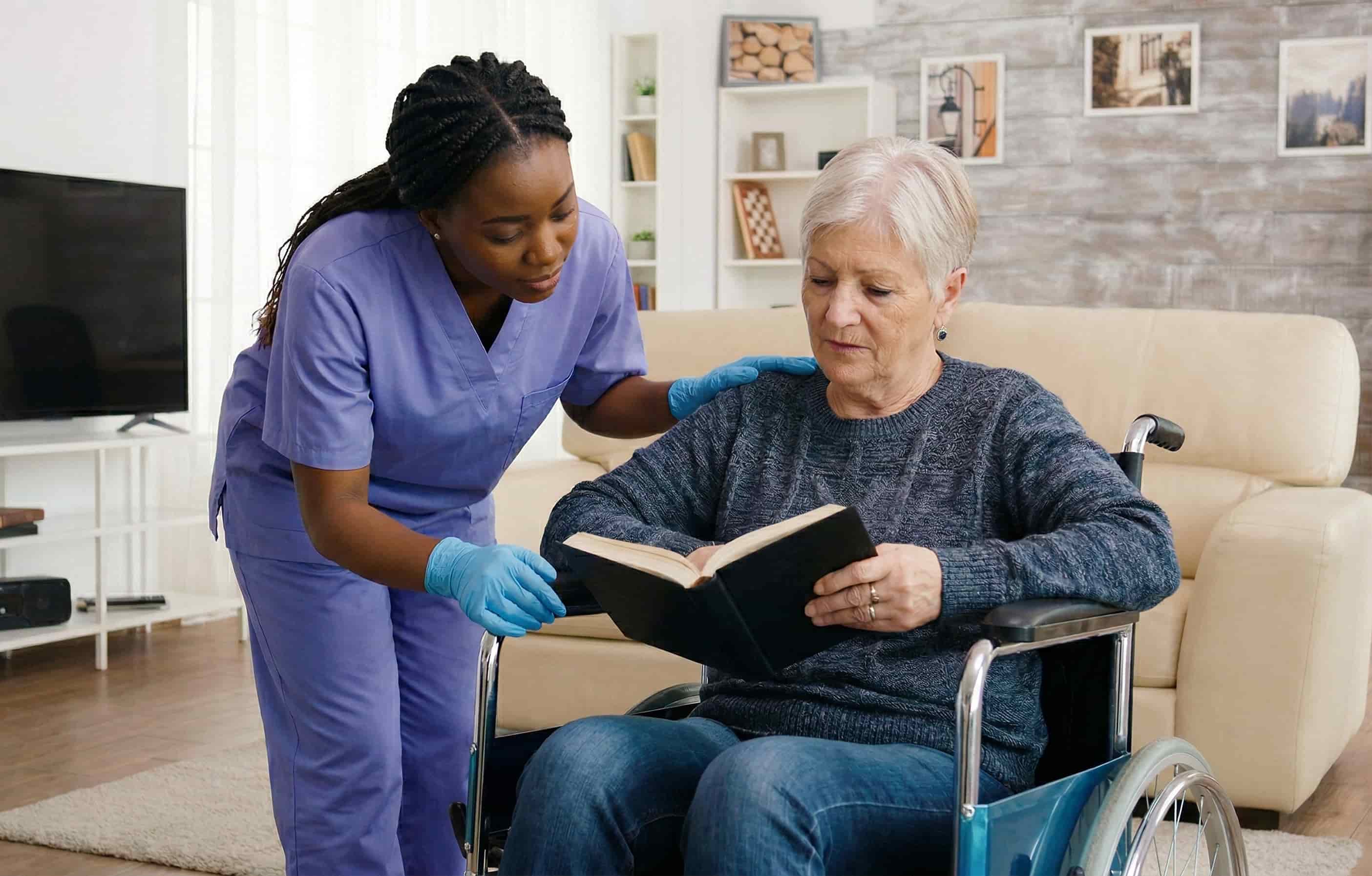 Home care professional reading a book with a senior woman in a wheelchair for engaging companion care.