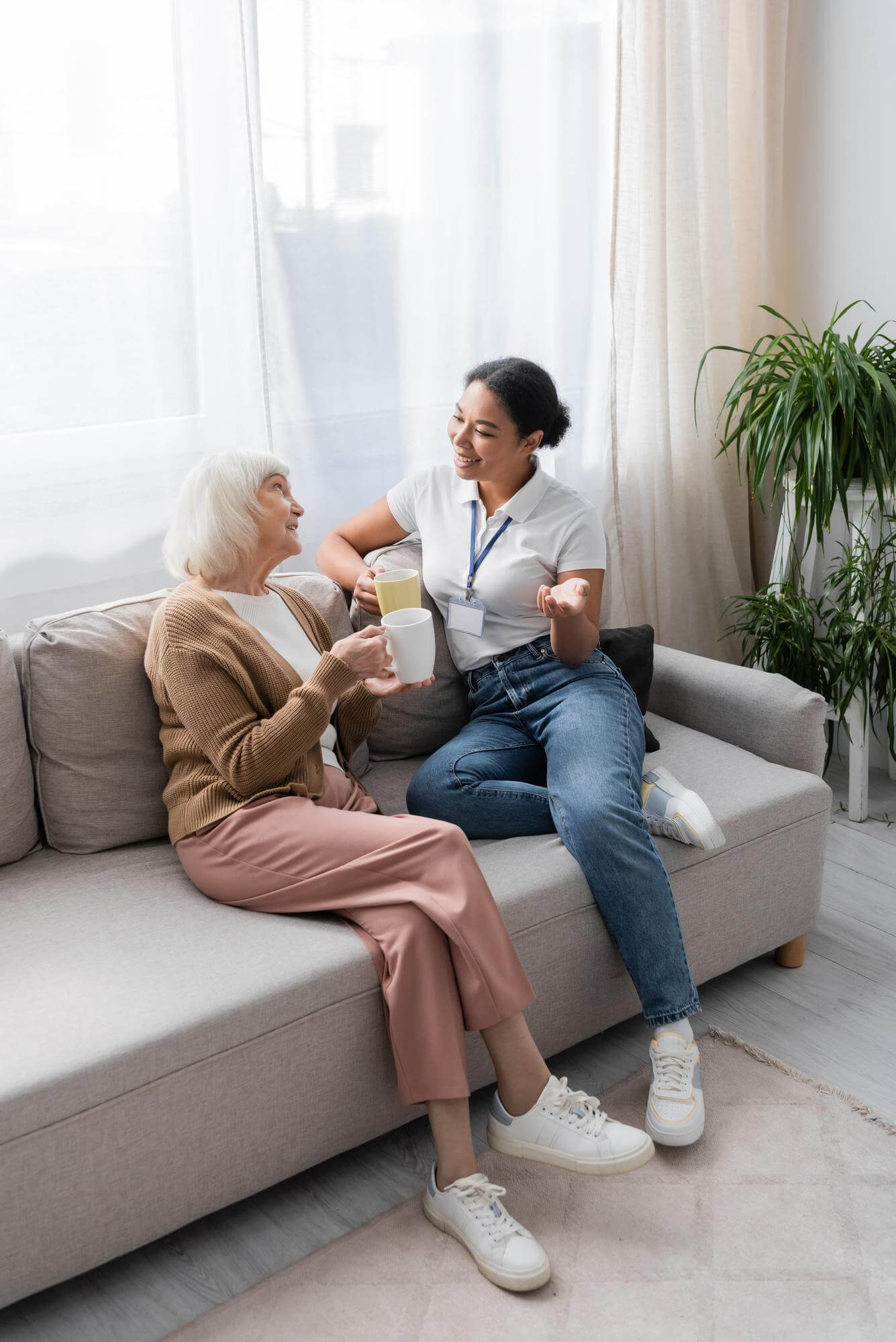 Happy multiracial social worker chatting with senior woman.