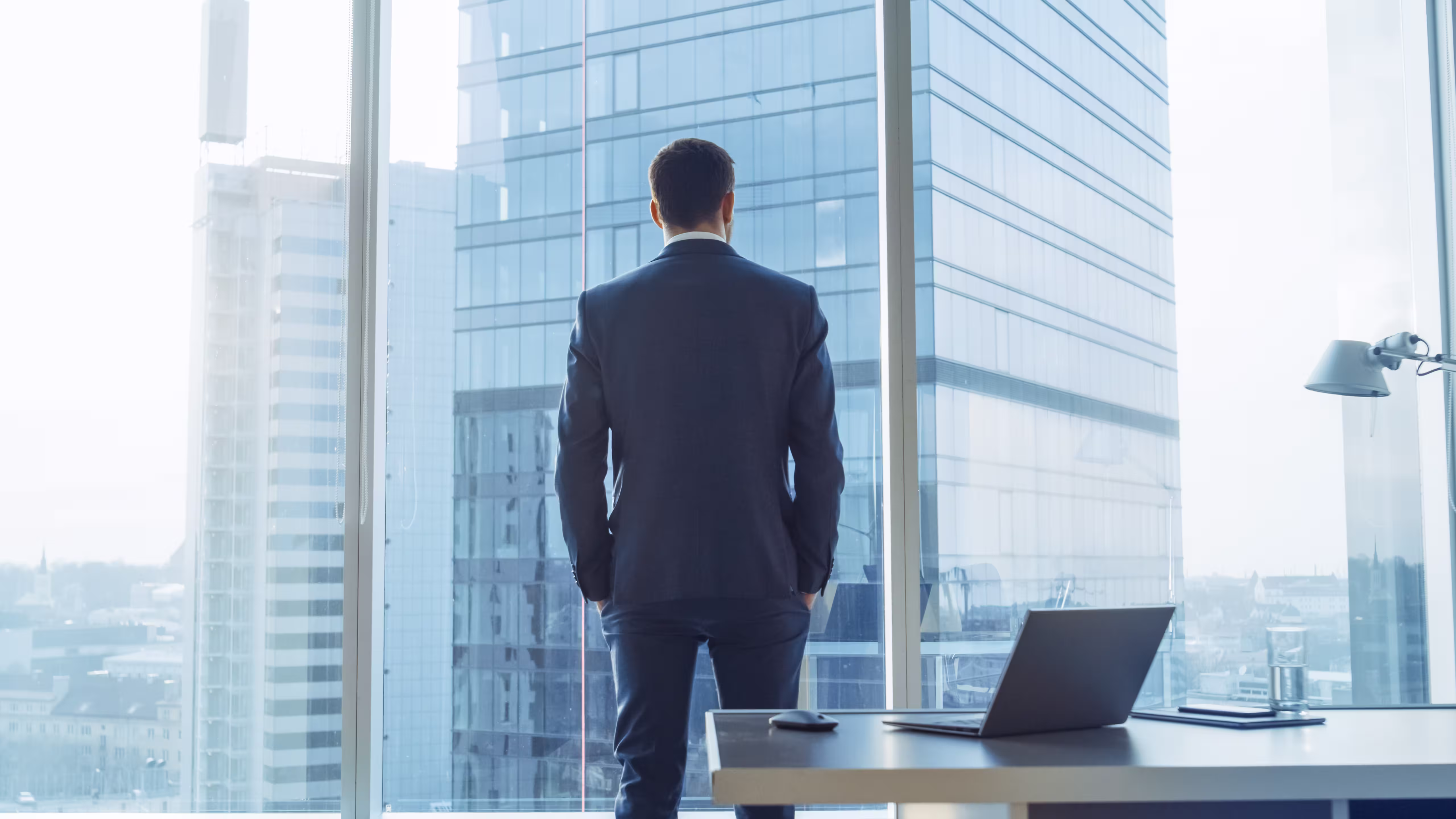 man looking out from his office building to the outside