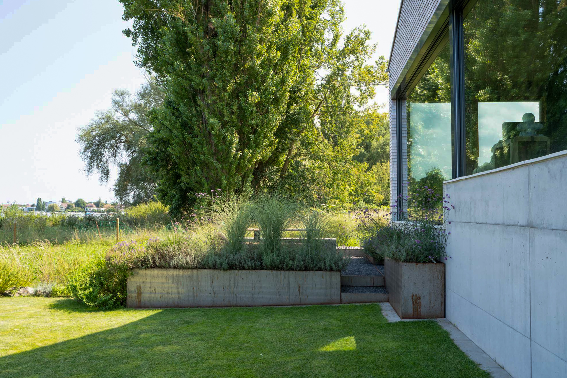 Beton Hochbeete mit Gräser Bepflanzung in einem wunderschönen Garten am See.