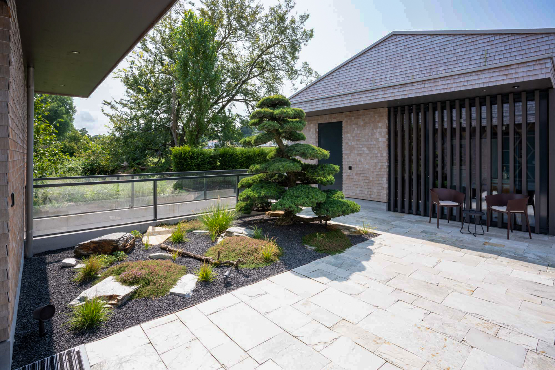 Garten mit Kiesbeet und Bonsai beim Hauseingang. 