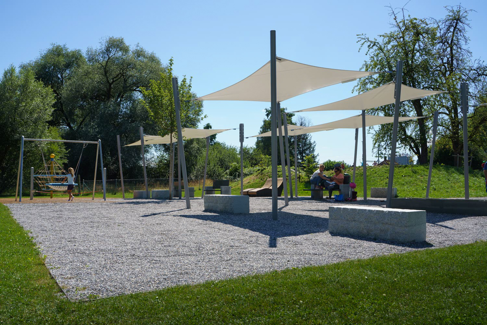 Spielplatz am Bodensee in der Salmsacherbucht mit Sitzgelegenheiten im Schatten. 