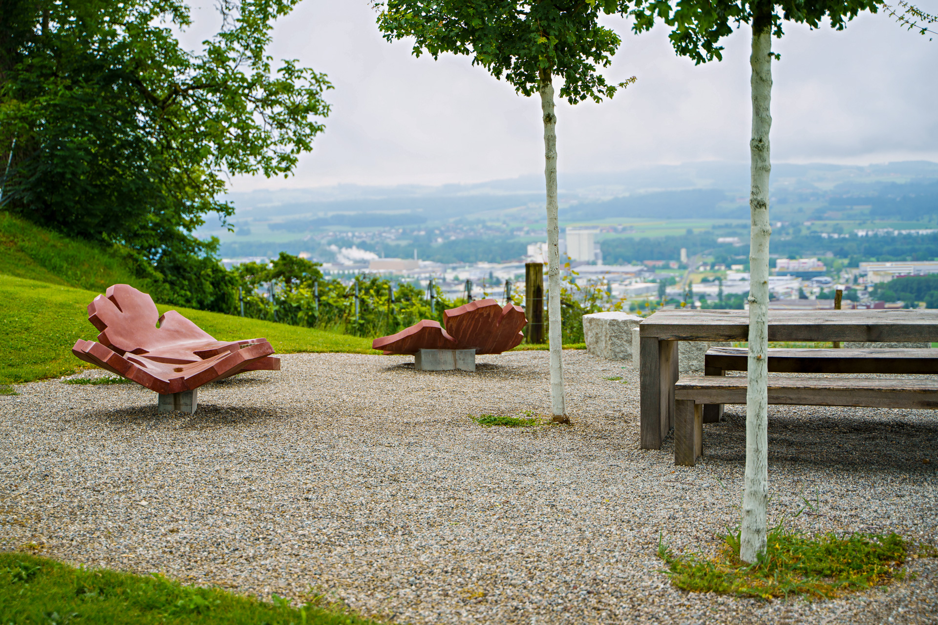 Sitzplatz mit Kunstwerk Sitzgelegenheiten als Weinblätter im Hintergrund die Stadt Weinfelden. 