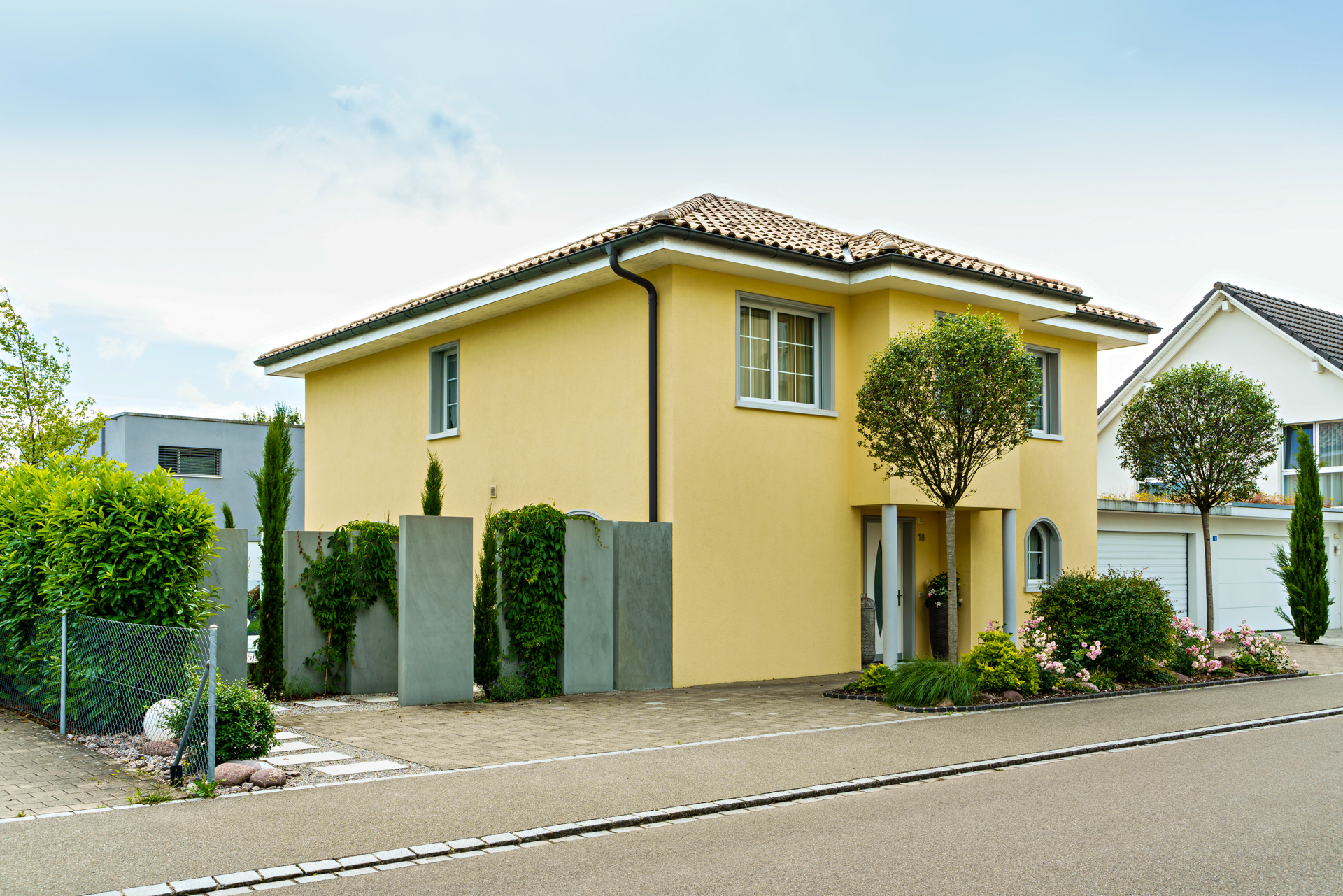 Einfahrt zu mediterranem Einfamilienhaus mit gelber Fassade in Weinfelden. 