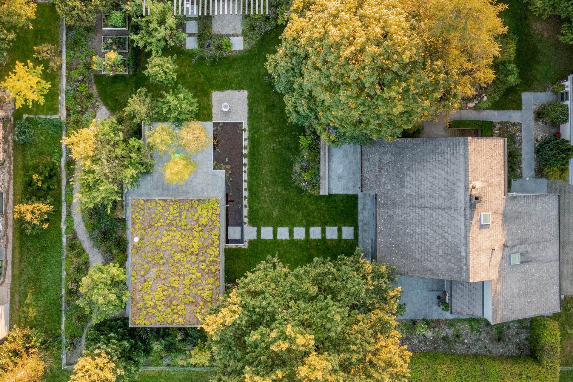 Drohnen-Aufnahme von einem privaten Grundstück mit einem grossen Haus und einer Loggia mit Wasserbecken und grossen Bäumen. 