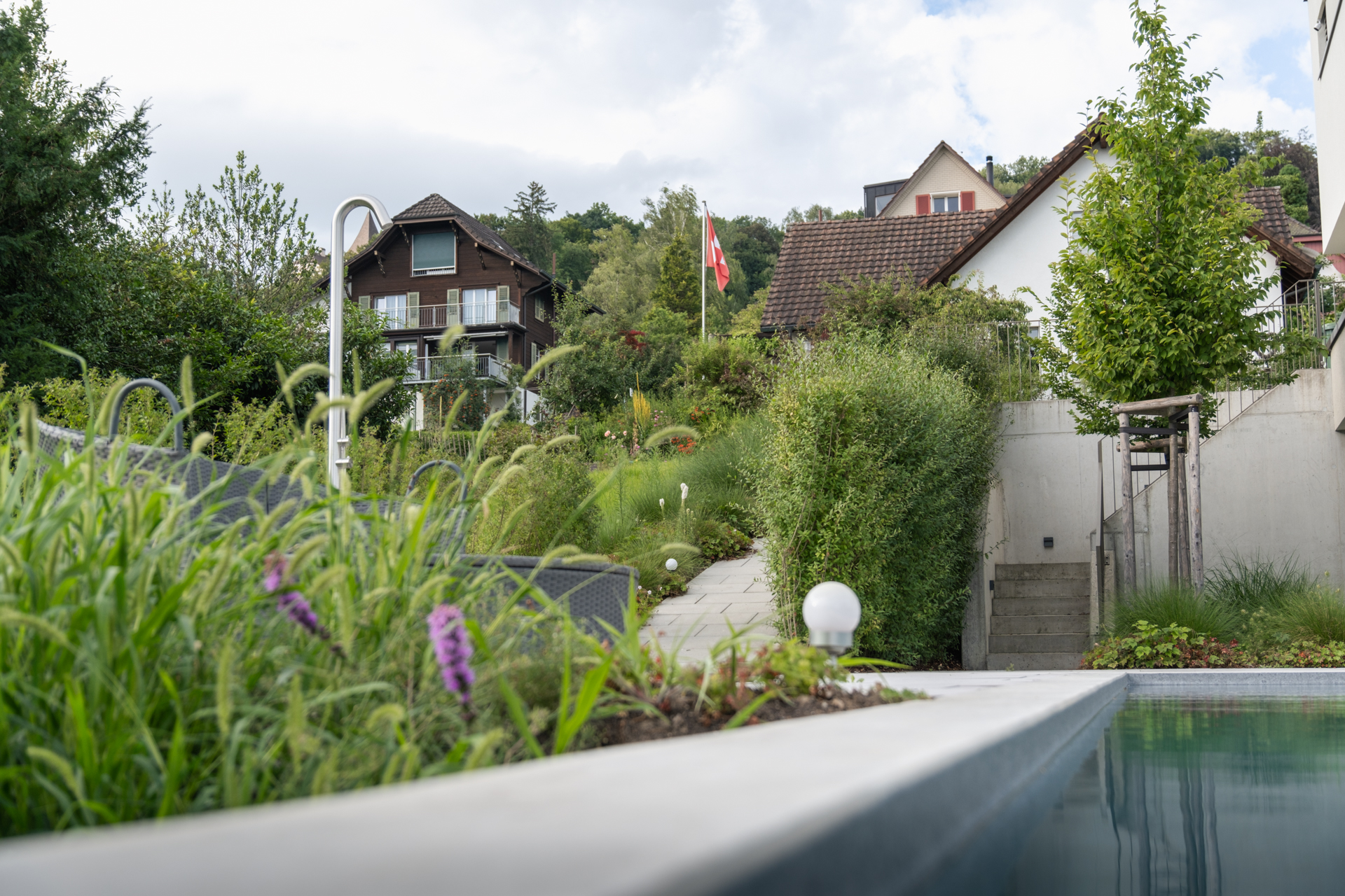 Nahaufnahme eines Swimmingpool mit Outdoordusche in modernem Garten. 