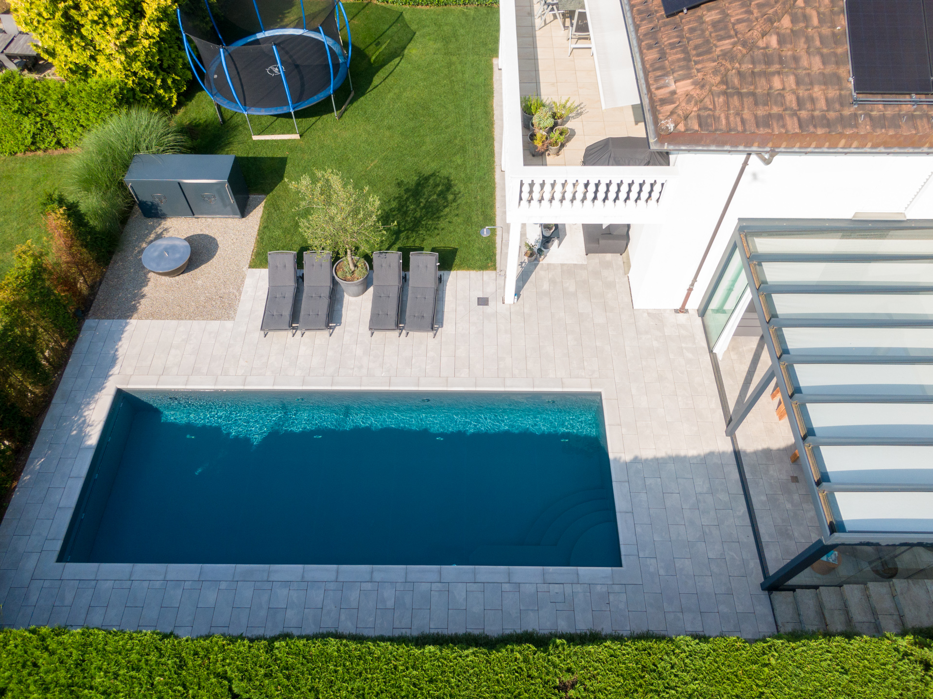 Modernes Haus mit Swimmingpool, Trampolin, Liegestühlen und Wintergarten. 