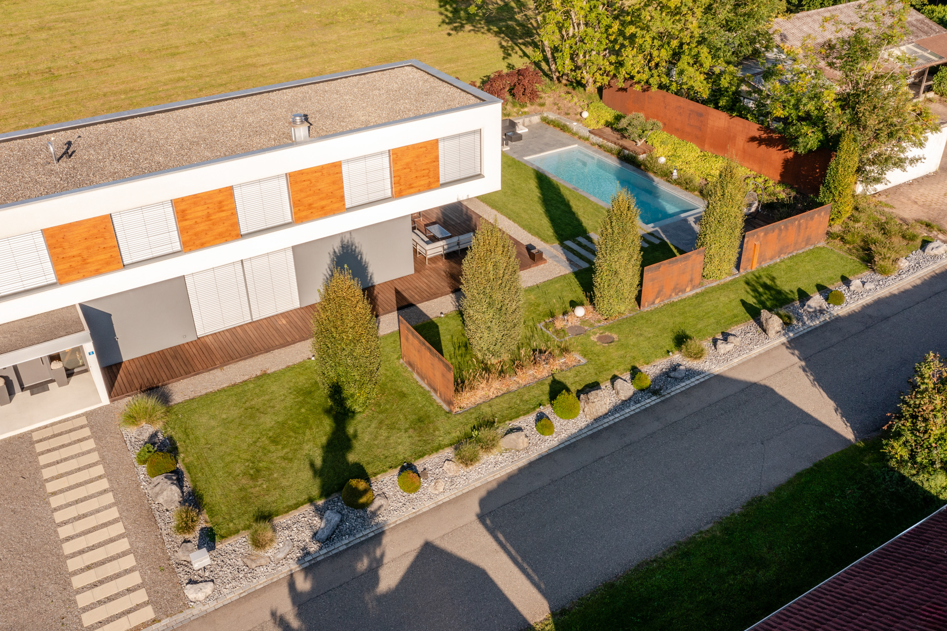 Foto aus der Vogelperspektive eines modernen Hauses mit geradliniger Gartenplanung und Swimmingpool. 