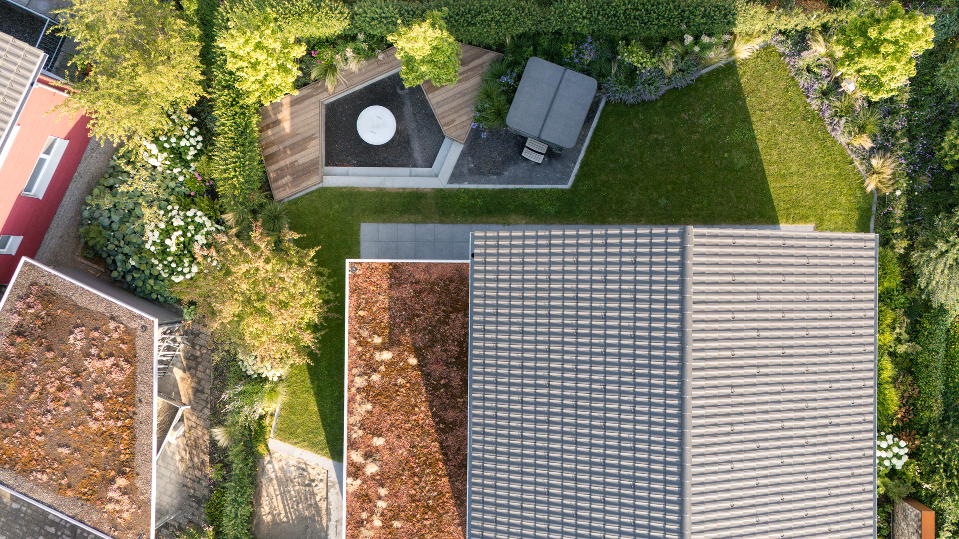 Modernes Haus mit Dachbegrünung und einem grossen Garten mit Whirlpool Feuerschale und Holzsitzgelegenheit. 