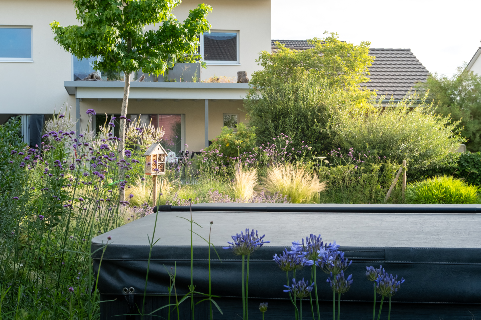 Ein Whirlpool in einem schönen Garten umringt von blauen und violetten Blüten. 