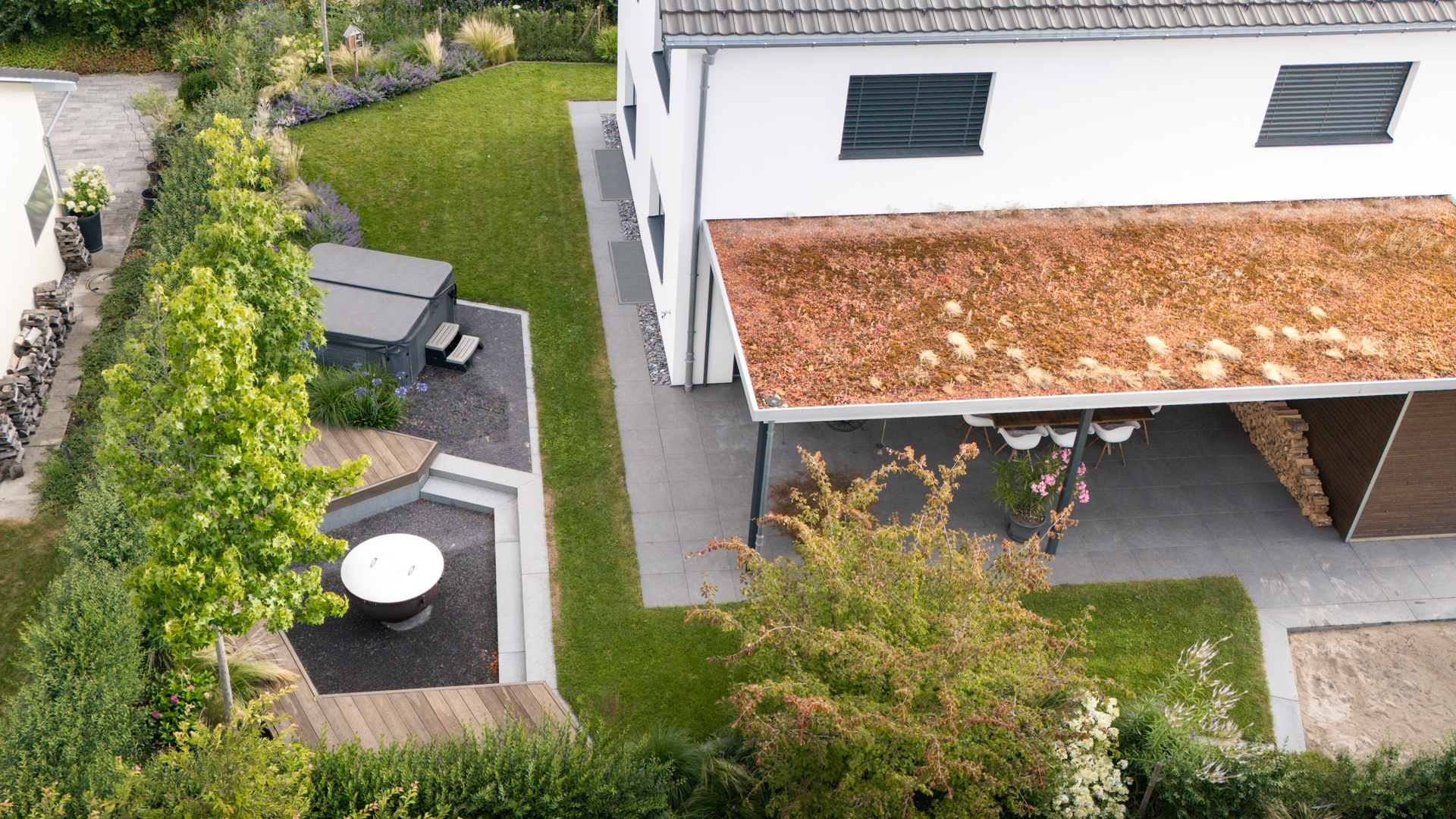 Foto aus der Vogelsansicht mit begrünter Loggia einem Whirpool und einer Feuerschale. 