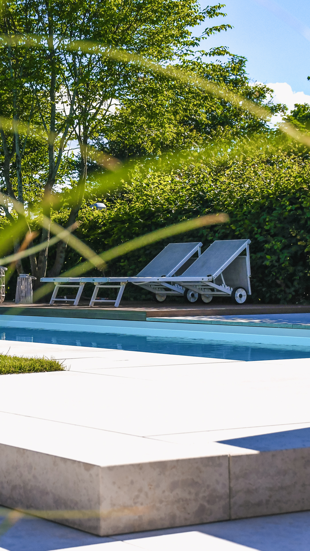Liegestühle am Rand eines in Beton gekleideten Swimmingpools.