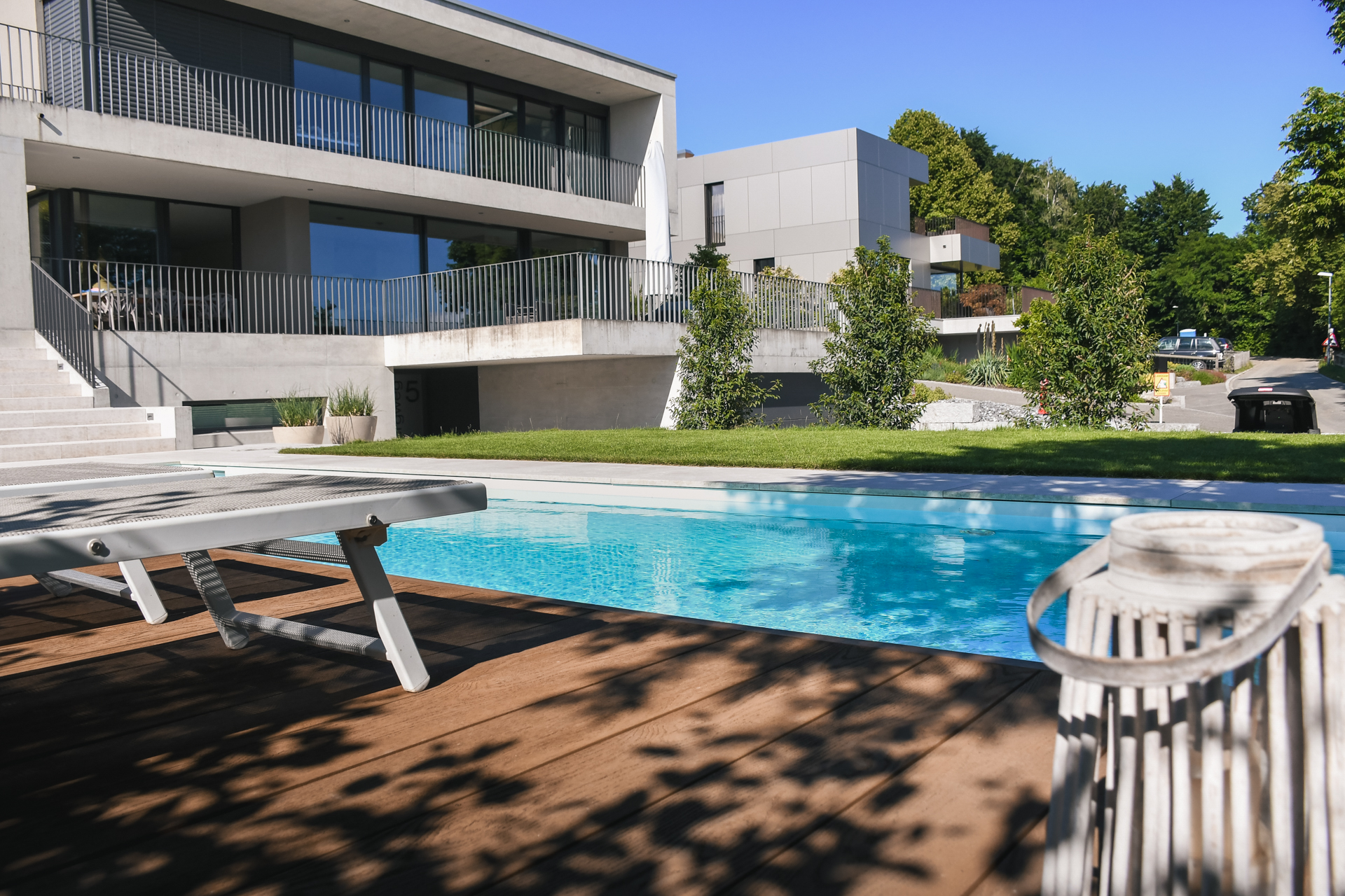 Beton Villen und ein grosser Swimmingpool mit saftig grüner Wiese. 