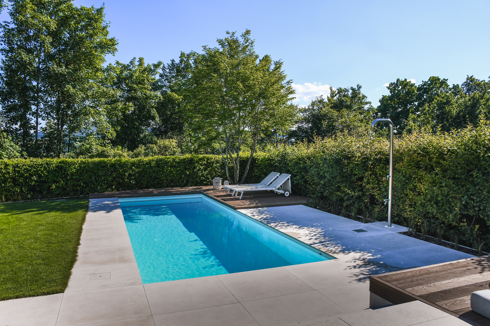 Swimmingpool mit grossen Natursteinplatten und einer Outddor Dusche im Thurgau. 