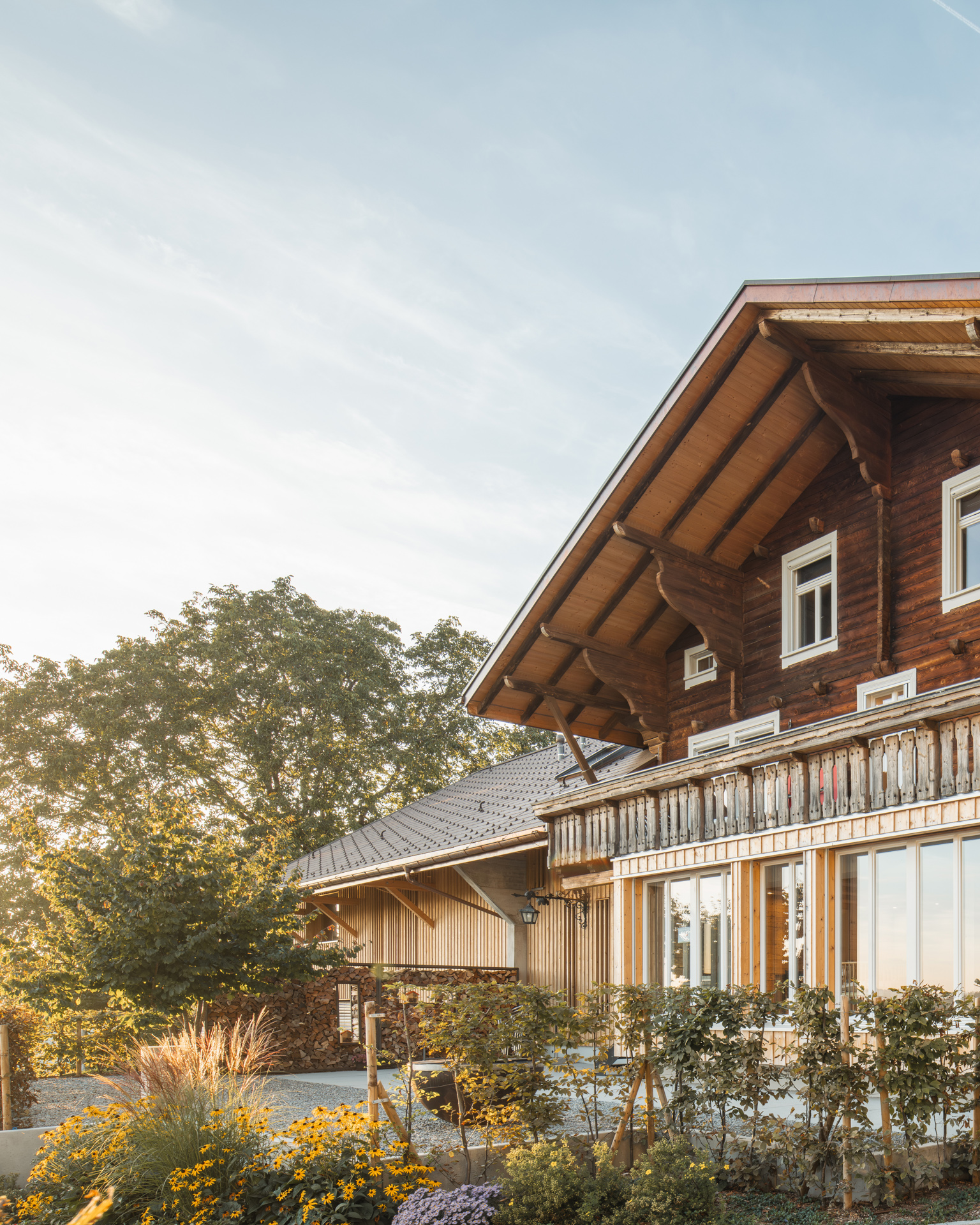 Wunderschönes Bauernhaus geflutet von Sonnenuntergangslicht mit schönem Garten mit gelben Blüten und Gräsern. 